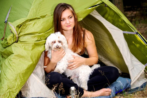 Junge Frau sitzt mit Hund vor ihrem Zelt — Stockfoto