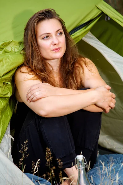 young brunette woman sitting outside in front of her tent