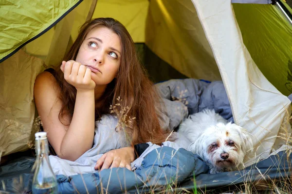 Junge Frau liegt mit ihrem weißen Hund im Zelt — Stockfoto