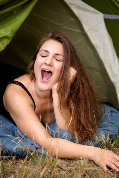 Giovane donna bruna sdraiata in tenda e sbadigliando — Foto Stock