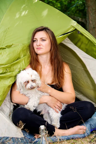 Junge Frau sitzt mit Hund vor ihrem Zelt — Stockfoto