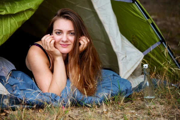 Giovane donna bruna sdraiata in tenda e guardando fuori — Foto Stock