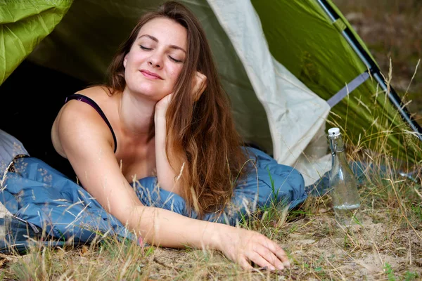 Young brunette woman lying in tent with her eyes closed — Stock Photo, Image