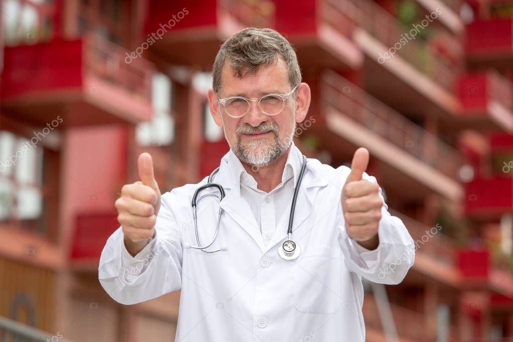 handsome doctor in his 50s standing outside with his thumbs up