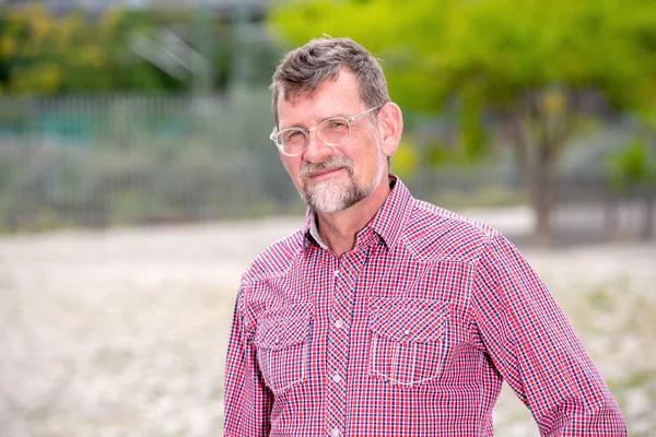 Knappe man in zijn 50s met geplaviel shirt staande buiten — Stockfoto