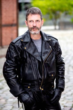 siyah deri ceket ve pantolon giyen yakışıklı sakallı adam