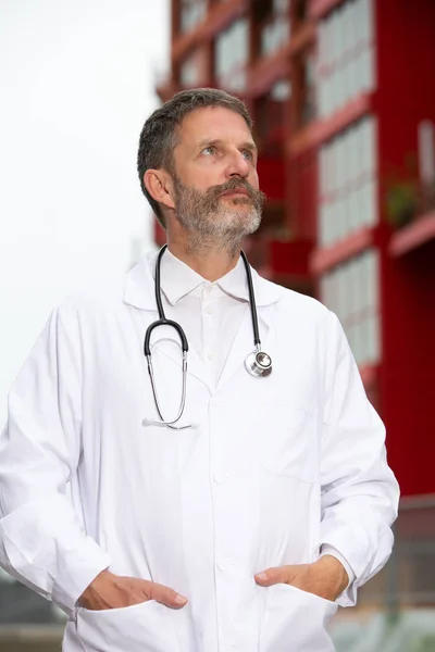Jóképű szakállas orvos fehér kabátot kívül álló — Stock Fotó