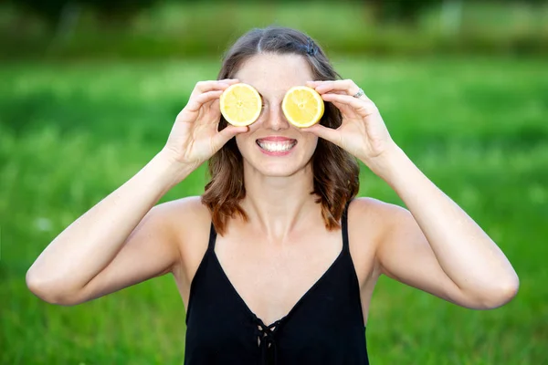 Jovem segurando um limão fatiado na frente de seus olhos — Fotografia de Stock