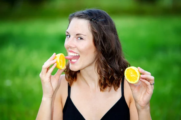 Jovem mulher ao ar livre segurando um limão e lambendo sobre ele — Fotografia de Stock