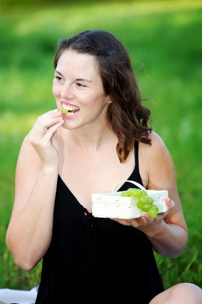 Young woman outdoors holding a basket with grapes — Stock Photo, Image