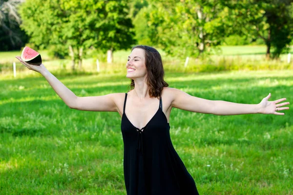 Junge brünette Frau hält eine Scheibe Wassermelone — Stockfoto