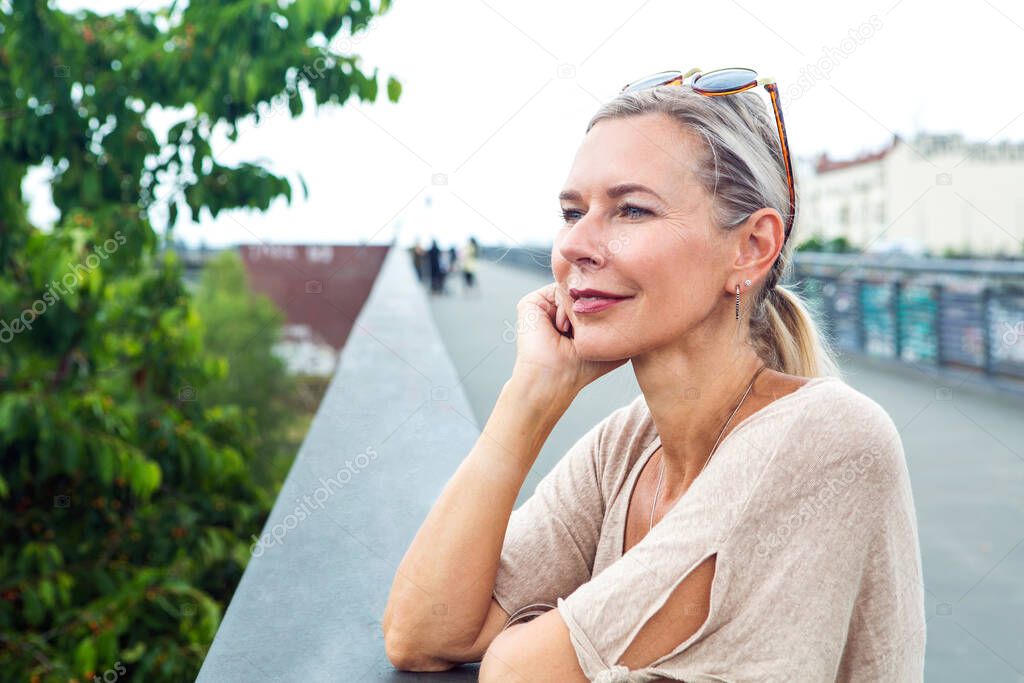 portrait of blond woman standing on bridge and looking serene