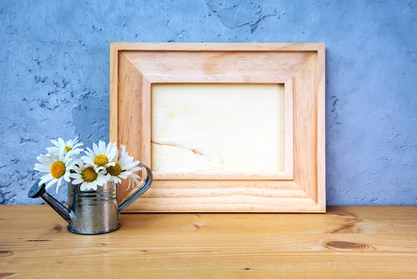 桌子上的木制画框 有迷你水壶和蓝色背景的雏菊 — 图库照片