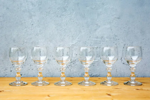 Close Van Rij Wijnglazen Houten Tafel Met Grijze Ondergrond — Stockfoto