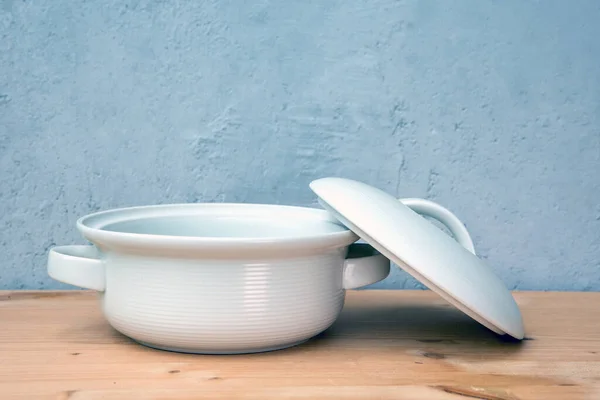 灰色の背景の木製のテーブルの上に蓋付きの白い鍋 — ストック写真
