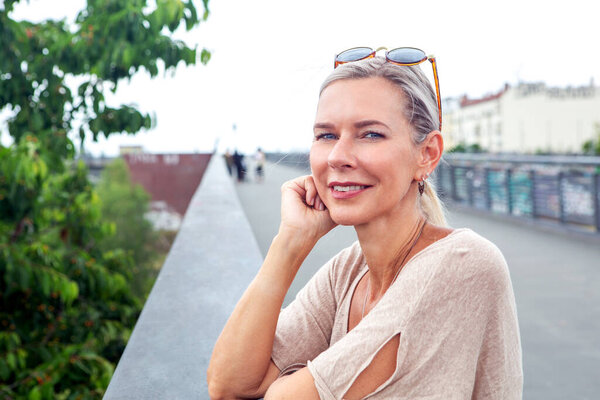 портрет блондинки, стоящей на мосту и выглядящей безмятежно
