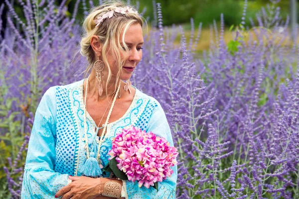 紫色の花の分野に立つ40代のブロンド女性の肖像画 — ストック写真