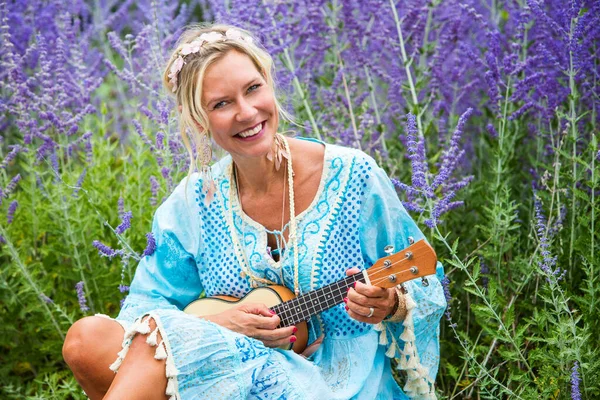 Blond Kvinna Årsåldern Sitter Fältet Blommor Och Spelar Gitarr — Stockfoto