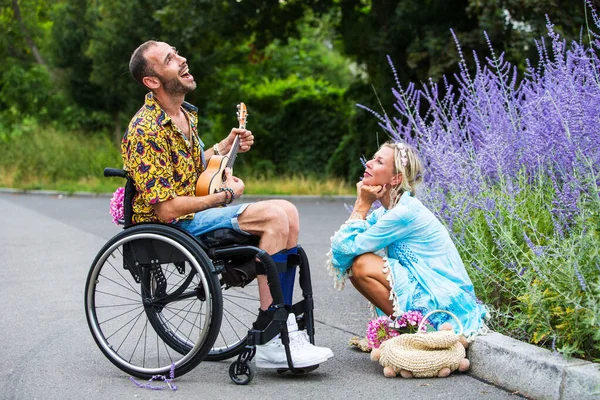Homem Cadeira Rodas Livre Tocando Guitarra Para Mulher Loira Sentada — Fotografia de Stock