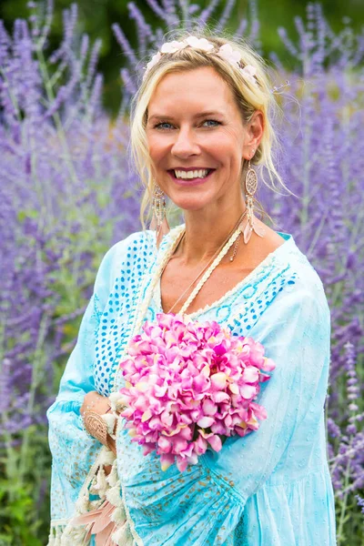 紫色の花の分野に立つ40代のブロンド女性の肖像画 — ストック写真