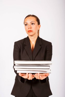 Takım elbiseli sarışın bir kadın bir yığın kitap tutuyor ve stresli görünüyor.
