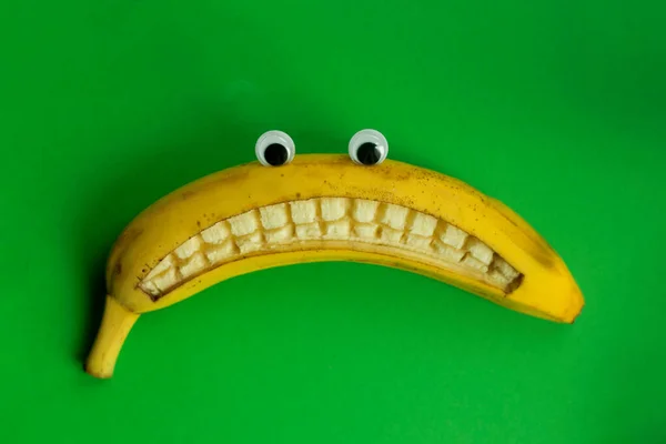 Banan Zabawkowymi Oczami Smutnym Uśmiechem Zielonym Tle — Zdjęcie stockowe