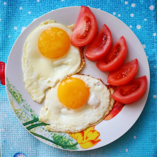Πρωινό φαγητό τηγανητά αυγά με ντομάτες σε ένα πιάτο — Φωτογραφία Αρχείου