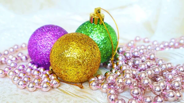 Christmas shiny golden green and purple balls with garland on a light background Royalty Free Stock Images