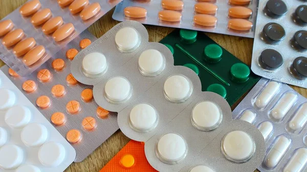 Medicines many tablets of orange white and green in a blister on the table