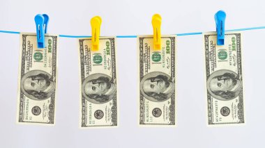 Para birimi, arka planında mandal olan bir ipe 100 dolar basıyor.