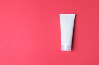 Kırmızı renkli arka planda kremalı tüp kopyalama alanı ile.