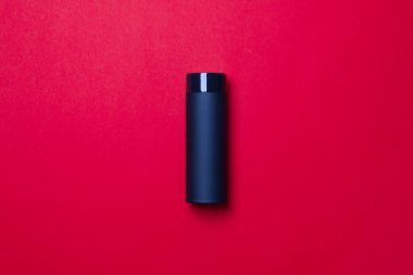 Kapalı fincanlı siyah termos kırmızı arka planda yatıyor. Üst Manzara. yakın plan.