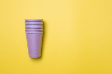 Bir çift çevre dostu karton bardak, fotokopi alanı olan sarı bir arka planda yatıyor. Model-up. Yakın plan. Ekoloji kavramı.