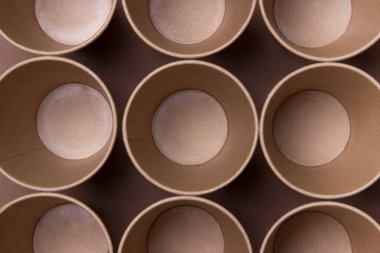 Kahverengi arka planda kahverengi karton çevre dostu bardaklardan yapılmış. Üst Manzara. yakın plan.