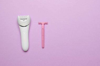 kadın epilator ve pembe jilet mor renkli kağıt arkaplan, kopya alanı ile üst görünüm.