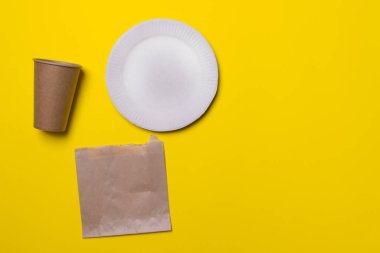Çevre dostu mutfak gereçleri, tabak, fincan, çanta, sarı renkli kağıt arka plan. Üst Manzara. Yakın plan. Boşluğu kopyala.