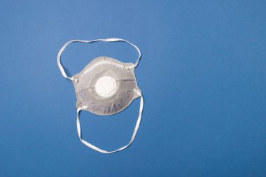 Mavi renkli kağıt arka planda koruyucu tıbbi yüz maskesi.