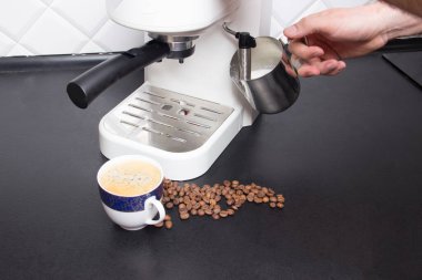 Modern mutfakta beyaz espresso kahve makinesinde kapuçino yapan adam..