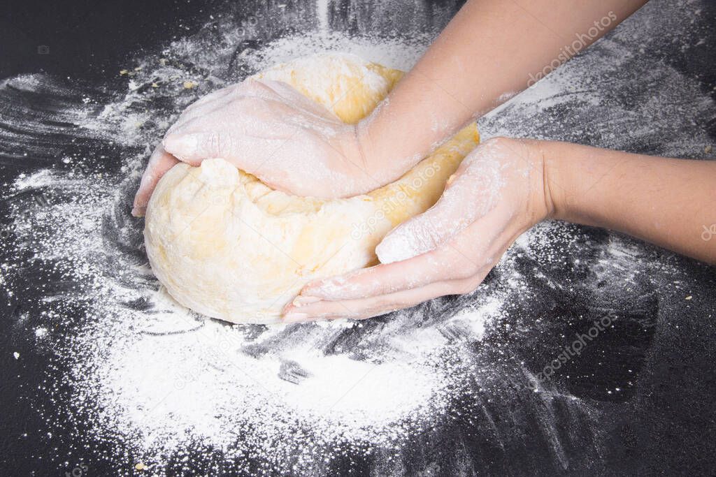 woman make dough for homemade bread on black table.