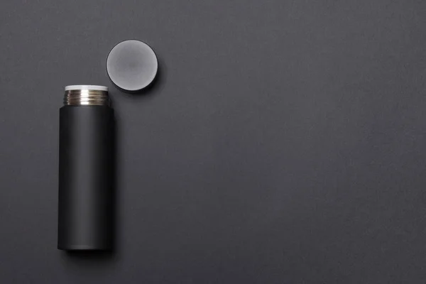 black thermos cup with open cover on black background with copy space.