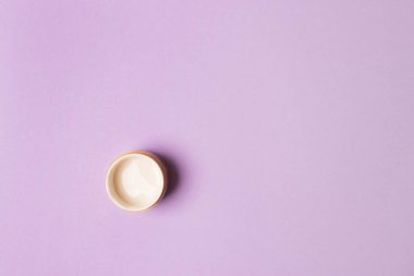 mor arka planda krema ile açılmış kavanoz. Kopyalama alanı olan üst görünüm.