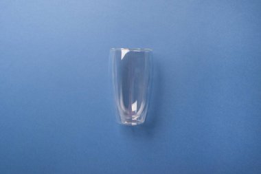 boş latte bardağı mavi renkli kağıt arka planda.