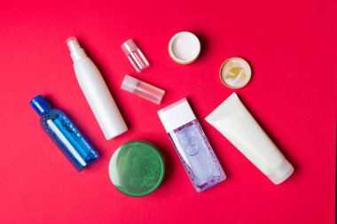 Kırmızı arkaplanda bir grup kozmetik şişe.