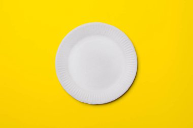 Beyaz çevre dostu kağıt tabak, sarı renkli kağıttan arka plan. Üst Manzara. maketleme.