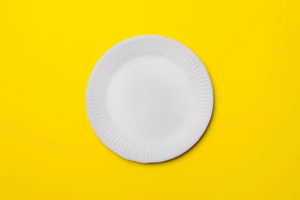 white eco-friendly paper plate on yellow colored paper background. top view. mock-up.