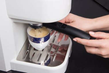 Kadınlar siyah mutfakta beyaz espresso kahve makinesinde espresso yaparlar..
