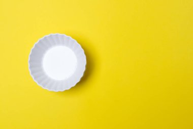 Kopyalama alanı olan sarı renkli kağıtta boş beyaz tabak.