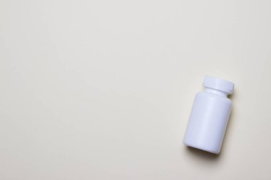 Sarı arkaplanın sağ tarafında fotokopi alanı olan haplar için beyaz plastik tıbbi kap.