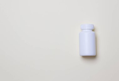 Sarı renkli kağıdın arka planında fotokopi alanı olan haplar için beyaz plastik tıbbi kap.