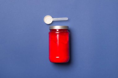 Kırmızı banka, toz ve kaşıkla mavi renkli kağıt arka planda.